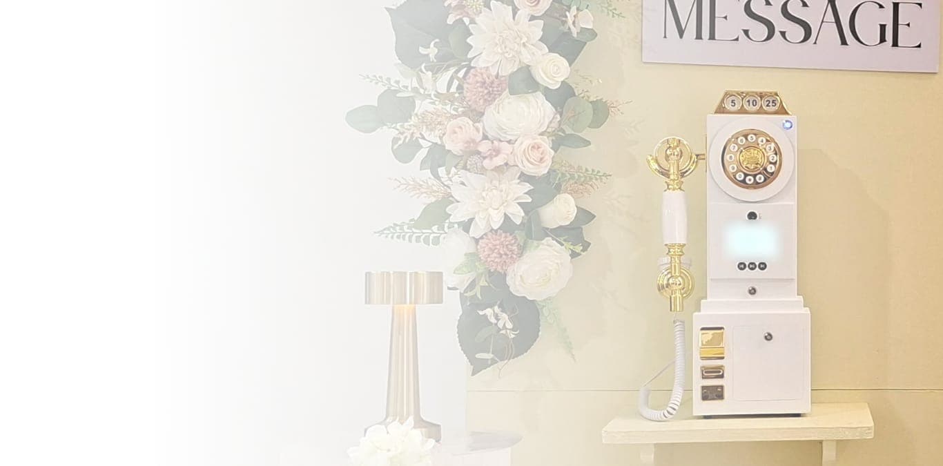 The VidBook phone booth set up at a reception, with a cascade of ivory and blush flowers